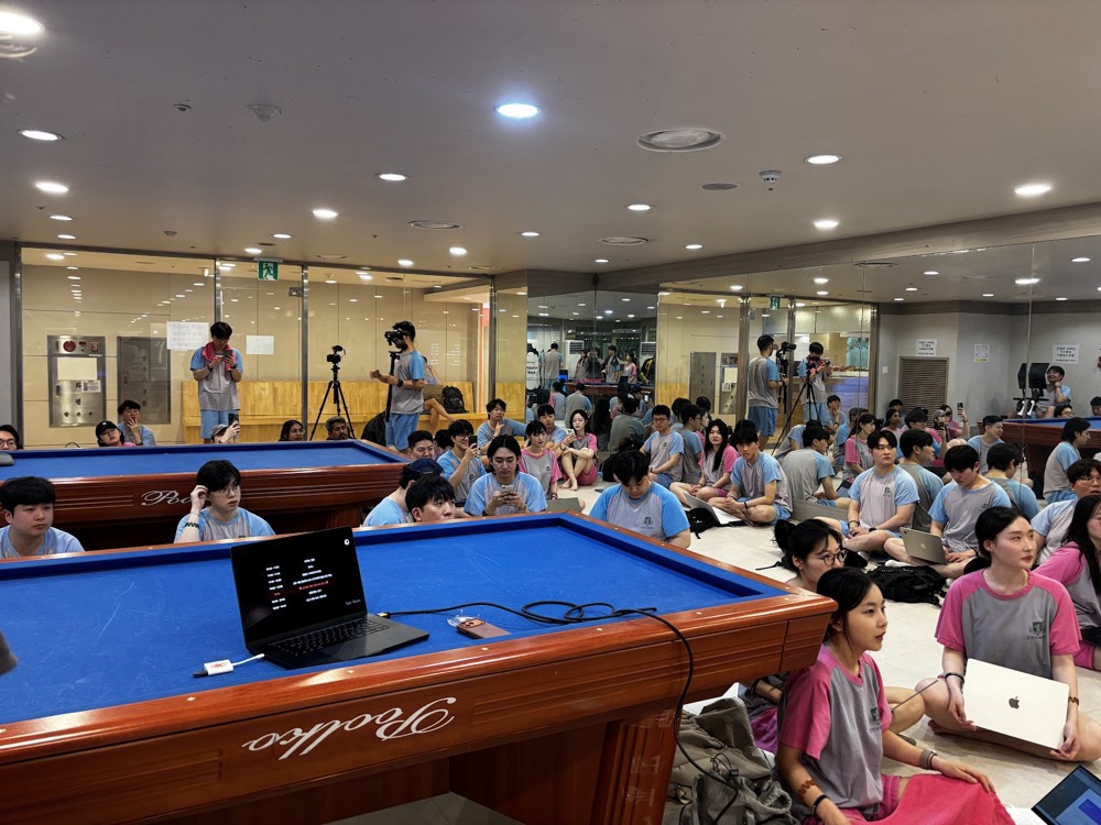 Builders in sauna robes coding on the floor around a pool table at Gangbyeon Spa Land