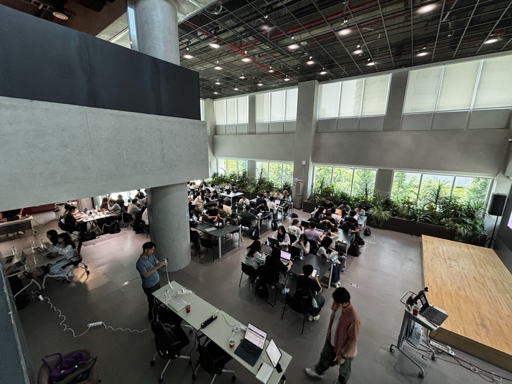 The Seoul AI Hub atrium full of builders at work, seen from above